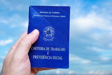 Brezilya Çalışma Kartı 'nı tutan adamın eli mavi gökyüzü ile izole edilmiş. Portekiz Federatif Brezilya Cumhuriyeti, Çalışma Bakanlığı 'nda yazılmıştır. Çalışma ve Sosyal Güvenlik kartı. Brezilya iş konsepti.