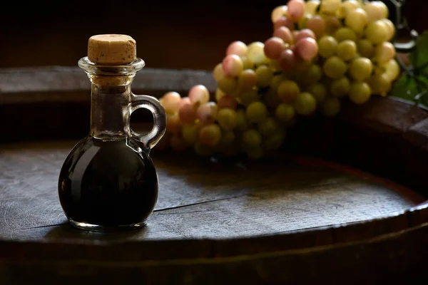 Traditional balsamic vinegar of Modena in a small bottle on a wooden barrel 
