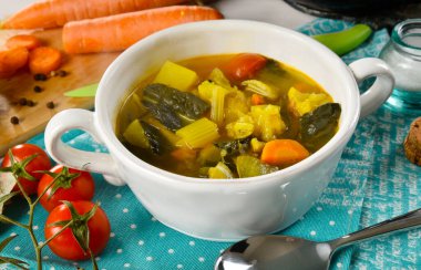 Beyaz bir seramik kasede büyülenmiş sebze çorbası, içinde bazı malzemeler var.