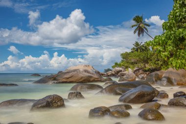 Tropikal bir adada bulutlar ve kayalık plajlar