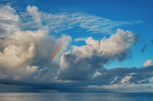 Rainbow over the ocean and tropical island Stock Photo