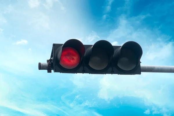 Red traffic light signal stands out under the blue sky.