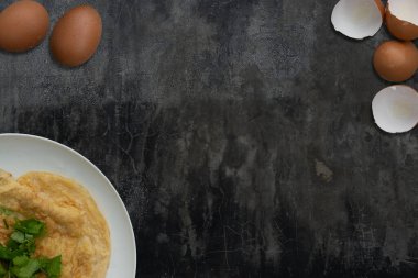 Kolay menü omlet menüsünün üst görüntüsü beyaz bir tabakta düzenlenir. Yumurta ve yumurta kabuğuyla dolu. Beton zemine metin içeriği eklemek için ortaya boş bir alan.