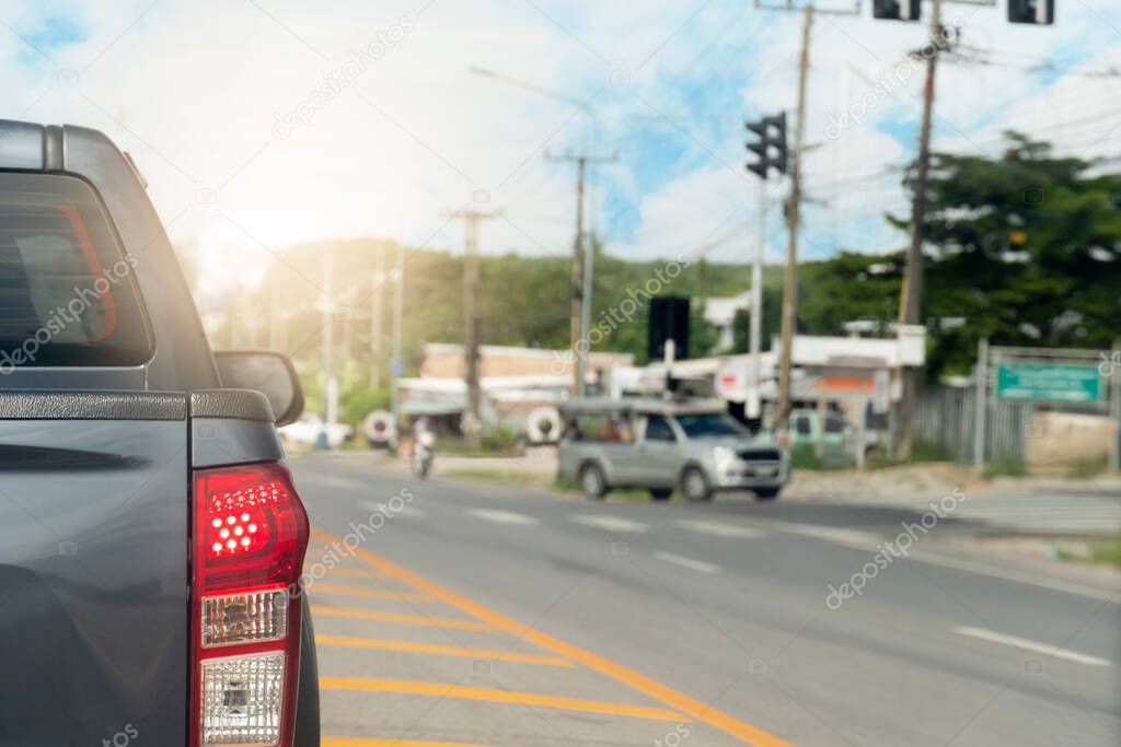 Rear side of pick up car driving on the asphalt road in the city. During daytime. Wait for the traffic lights at the crossroads. with open brake and turn signal light.