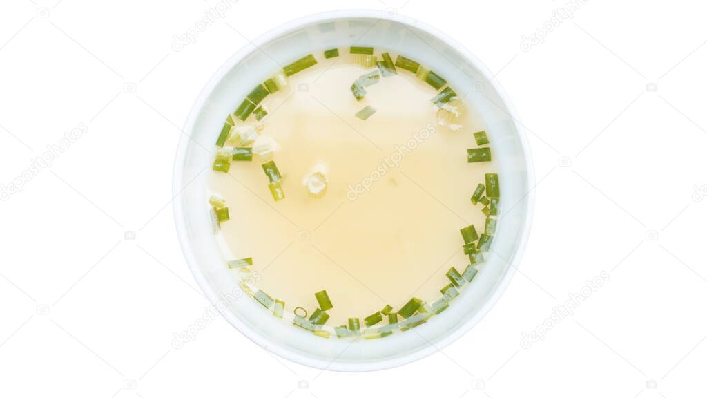 Above view of Hot broth sprinkled with chopped green onions and coriander. Inside white cup. On isolated white background with clipping path.