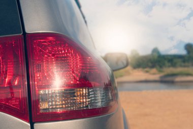 Arabanın arka tarafında, trafik lambasına yakın çekim. Toprak yola park etmek. Mavi gökyüzünün altındaki ağaç ve toplayıcının bulanık doğası..