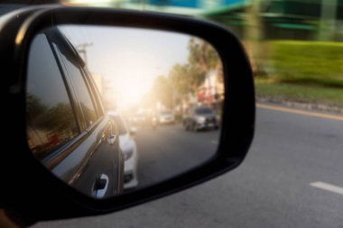 Gri bir arabanın ayna kanadının arkasından geçen trafik arabalarının soyut ve bulanık görüntüsü. Asfalt yolda hız ve arabanın yanında yeşil çimen.