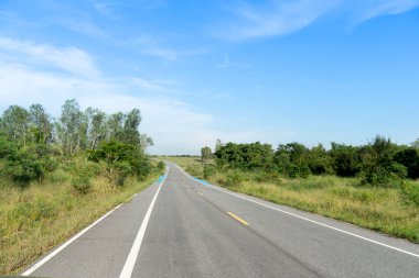Asfalt yolu ve Tayland 'da mavi bisiklet yolu üzerinde düz bir yol. Yeşil çimenlerin ve ağaçların yanında. Mavi gökyüzünün altında.