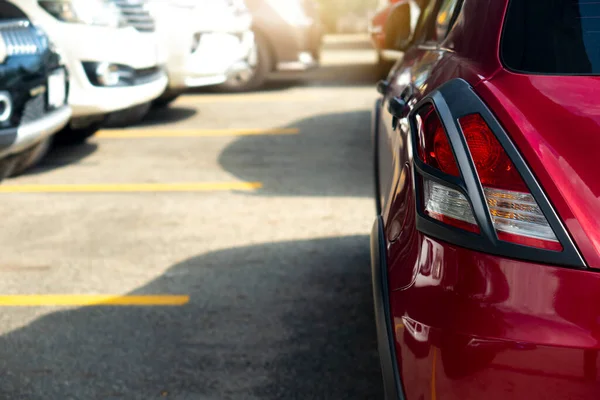 Yoldaki kırmızı arabanın arka tarafında yarış ya da park için hazırlan. Yolda geçici olarak engellenmiş. Otoparka park eden arabaların bulanık görüntüleri..