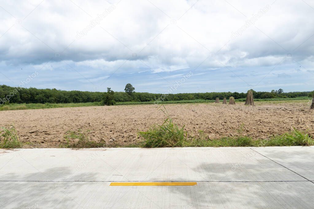 Horizontal view of concrete road in Thailand. Detailed patterns drawn on the road. Background of Land area prepared for farming. Under the sky before rainy.