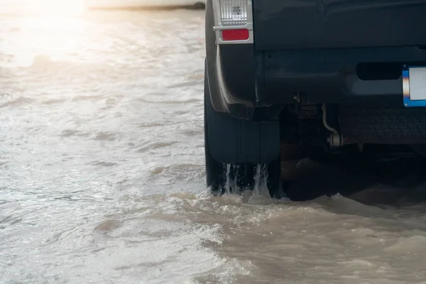 Under the wheels of a car that wades through water. Flooded water filled the road surface.