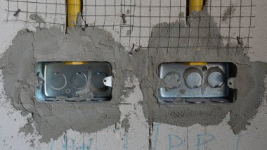 Evin duvarlarına gömülmüş iki kutu demir blok. Sarı bir PVC boru akıyordu. Binadaki elektrik tesisatı hazırlanıyor..