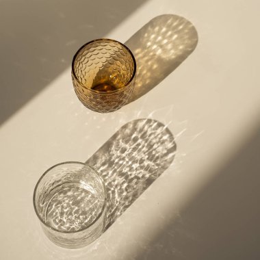 Minimum lüks modern iç tasarım konsepti. Tarafsız bej arka planda parlak güneş ışığı gölgesi olan bohem kristal cam.