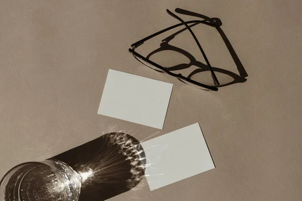空白纸卡片 带有模拟复制空间 最小的豪华波希米亚美学商业品牌模板 有阳光阴影的水晶玻璃杯 中性米色背景的眼镜 平躺在地上 俯瞰四周 — 图库照片