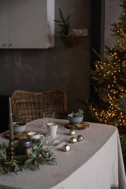 Modern ev iç tasarımı. Noel ağacıyla dekore edilmiş rahat bir oturma odası, rattan sandalye, keten kumaşlı masa. Noel, yeni yıl bayramı kutlama yemeği