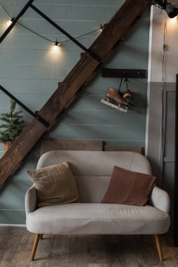 Modern İskandinav Hygge tarzı oturma odası iç tasarımı. Rahat rahat bir kanepe, yastıklı, parlak çelenk ışıkları, merdivenler, mavi duvar. Zarif Noel, Yeni Yıl kutlamaları