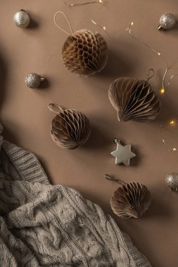 Ekose örgü, Noel ağacı süslemeleri, bej arka planda parlak çelenk ışıkları. Bohem Noel geçmişi. Düz yatış, üst görünüm