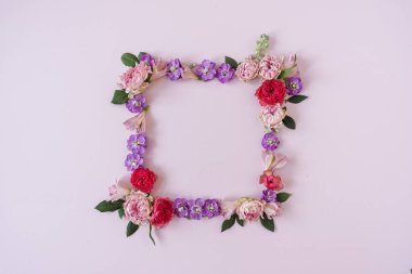Kare çerçeve çelengi. Pembe arka planda pembe gül çiçeklerinden yapılmış boş bir kopya alanı. Düz konum, üst görünüm minimal çiçek bileşimi.