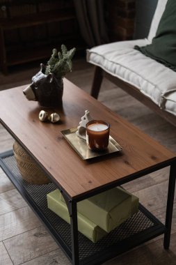 Konforlu rahat kanepe, ahşap sehpa, mum, köknar ladin dalı, dekor. İskandinav kızlık zarı stili