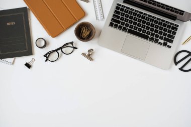 Estetik ofis masası çalışma alanı dizüstü bilgisayarı, not defteri, masa örtüsü, beyaz arka planda kırtasiye malzemeleri. Düz konum, üst görünüm günlüğü, web sitesi, temiz kopya alanı olan sosyal medya kavramı