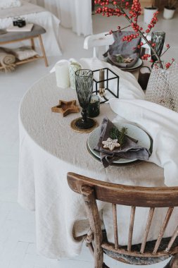 Noel yemeği servisi. İçi sandalye, masa, kırmızı böğürtlen buketi, tabak, bardak ve dekorasyonla dolu yemek odası. Yeni yıl, Noel arifesi kutlama akşamı