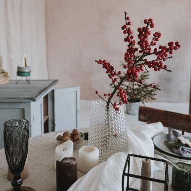 Noel yemeği servisi. Parlak yemek odası, tozlu pembe duvarlar, masa, kırmızı böğürtlen buketi, dekorasyonlar. Noel kutlaması akşamı