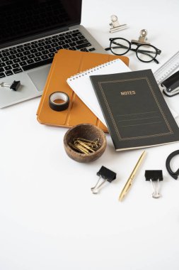 Laptop bilgisayar, tablet ped, beyaz masa arkaplanındaki notlar. Estetik minimal serbest yazar, blog yazarı ofis çalışma alanı