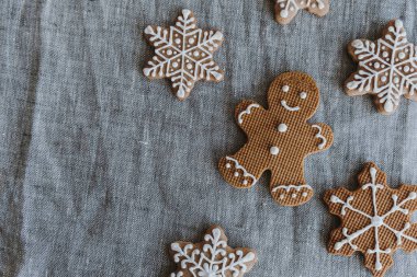 Gri keten masa örtüsünde ev yapımı zencefilli kurabiye. İnsan ve kar taneleri. Mutlu Noel kompozisyonu. Düz yatış, üst görünüm