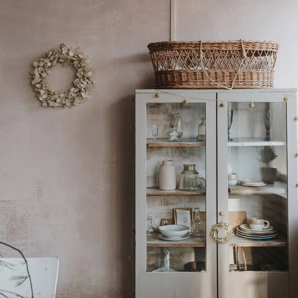 Elegant aesthetic home living or dinning room interior design with dinner table, linen table cloth, fir branch bouquet, Christmas wreath, neutral dusty pink walls with sunlight shadows