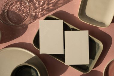Fotokopi alanı olan boş kağıt kağıdı. Minimum lüks, estetik, marka şablonu. Güneş ışığı gölgeli cam, tozlu pembe arka planda seramik plakalar. Düz yatış, üst görünüm