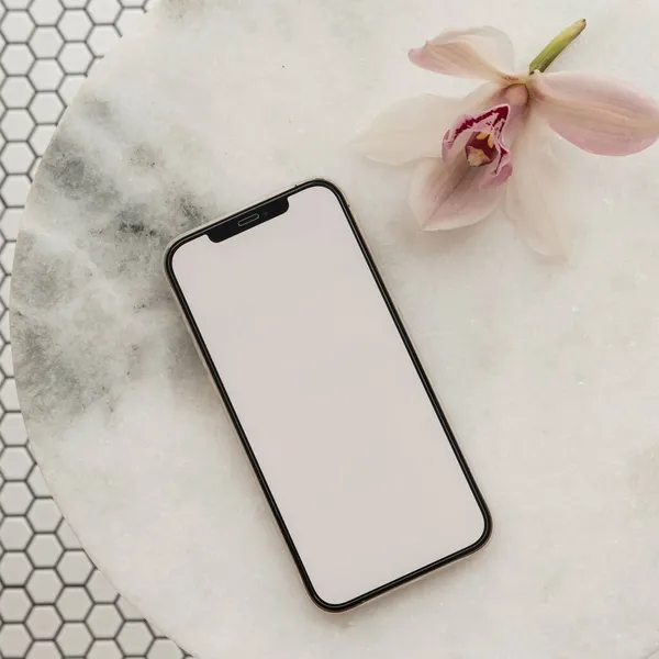 Blank clipping path screen mobile phone, pink flower on marble stone table on mosaic tile background. Aesthetic template with mockup space. Flat lay, top view