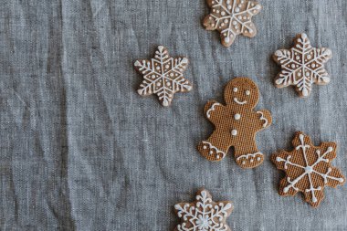 Tarafsız keten kumaş arka planda Noel kurabiyesi ve kar tanesi kurabiyesi. Düz yatış, üst görünüm