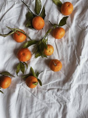 Turuncu mandalina manzarası ve buruşuk keten kumaş üzerinde yeşil yapraklar. Düz yatıyordu