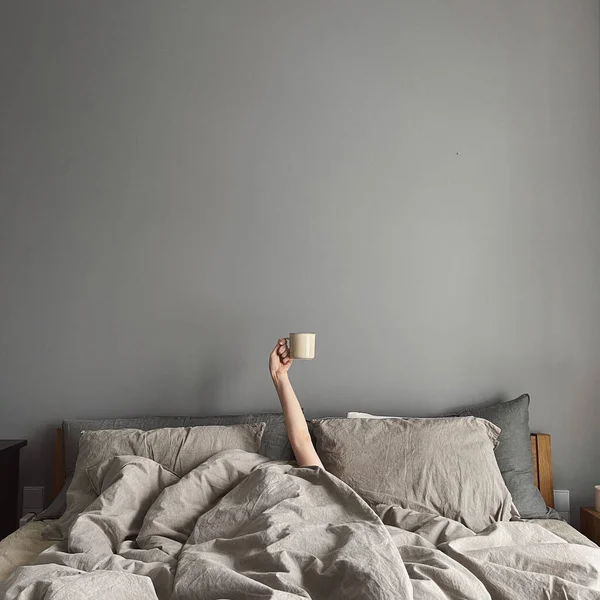 Χέρι Νεαρής Γυναίκας Κούπα Καφέ Στο Κρεβάτι Ουδέτερο Γκρι Λινό — Φωτογραφία Αρχείου