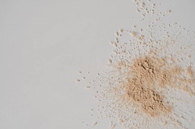 Beyaz arka plana dağılmış bej kozmetik tozu. Estetik güzellik ürünü konsepti. Düz yatış, üst görünüm