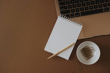 Boş kağıt çarşaf, fotokopi alanı, dizüstü bilgisayar, papatya çiçeği buketi. Estetik minimalist çalışma alanı düzlüğü. Üst görünüm