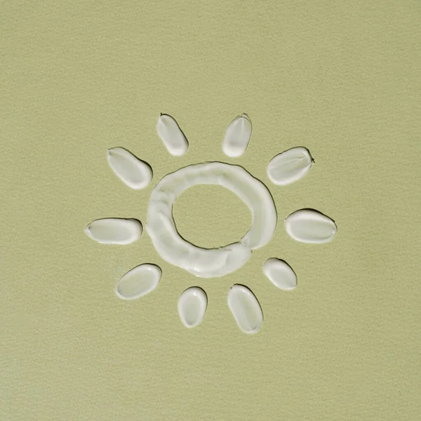 太阳符号是用白色乳霜涂成的 涂在绿色的背景上 美容美发产品概念 — 图库照片
