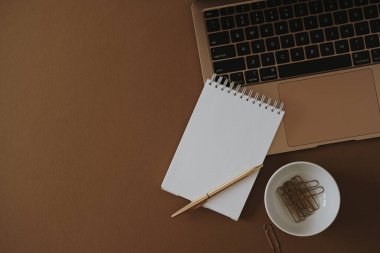 Ev konseptinde çalış. Estetik minimalist çalışma alanının düz hali. Fotokopi alanı ve bej arkaplanda dizüstü bilgisayarı olan defter kağıtları. Düz yatış, üst görünüm