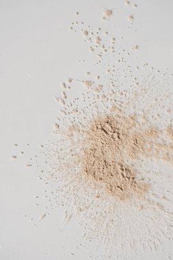 Güzellik, cilt bakım ürünleri. Beyaz arkaplana serpilmiş nötr bej kozmetik tozu