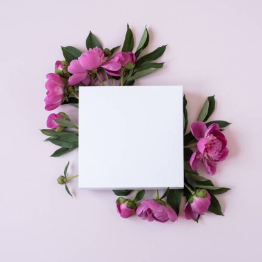 Zarif pembe şakayık çiçeklerinden yapılmış çelenk. Pastel pembe arka planda boş fotokopi kağıdı var. Düz yatak, üst görünüm markası, blog, web sitesi, sosyal medya şablonu