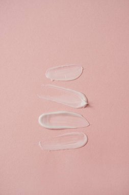 Pembe arka planda kozmetik krem lekesi var. Estetik güzellik ürünleri