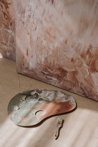 Estetik pembe boya bezi, palet, fırça. Sanatçı, güneş ışığı gölgeleriyle uzay resmi yapıyor. Minimalist zarif sanat eseri