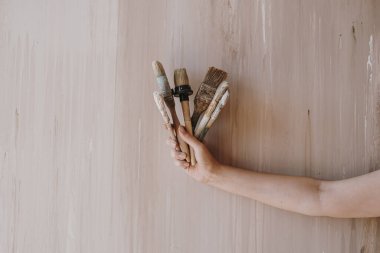 Tarafsız bej arka planda kadının el fırçası var. Minimalist sanat konsepti