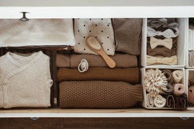 Flatlay estetik İskandinav bebek kıyafetleri, bebek bakım aksesuarları, saklama rafındaki oyuncak yığınları. Moda, zarif, nötr, pastel renkli bebek moda seti. Üst görünüm