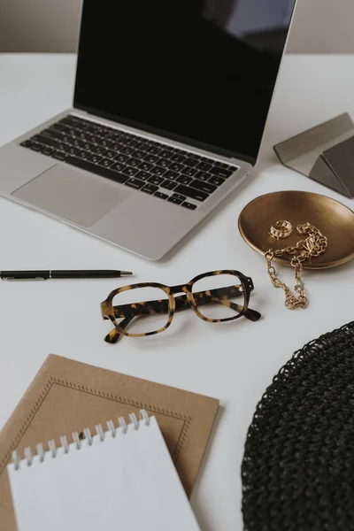 Aesthetic luxury fashion boutique branding composition. Elegant boho women\'s jewelry and accessories: glasses, ring, bracelet. Lady boss workspace with laptop computer and notebook. Flat lay, top view