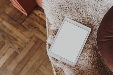 Rahat yün koltukta boş ekranlı tablet. Taklit alanı olan estetik şablon. Çevrimiçi mağaza, blog, sosyal medya, web sitesi markalaşması. Çevrimiçi alışveriş kavramı