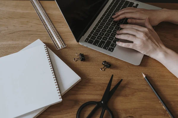 Aesthetic minimalist home office workspace desk. Person working on laptop computer. Notebook, stationery. Office work, business concept