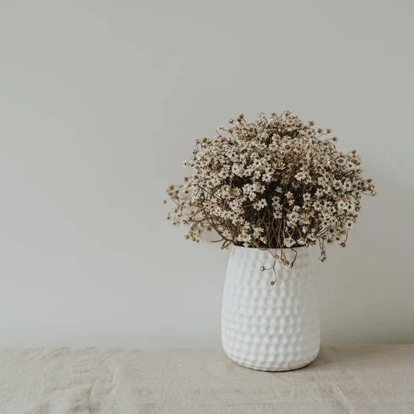 Aesthetic luxury bohemian flowers composition. Elegant gentle small daisy chamomile flowers bouquet in white vase