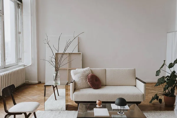 Aesthetic modern Scandinavian home interior design. Elegant living room with comfortable sofa, mid-century furniture, cozy carpet, wooden floor, white walls, home plants