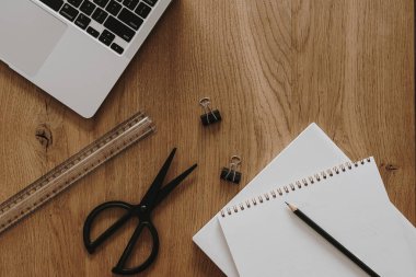 Laptop, defter, kahverengi ahşap masa zemininde kırtasiye malzemesi. Düzlük, üst görünüm estetik minimal serbest yazar, blog yazarı ofis çalışma alanı